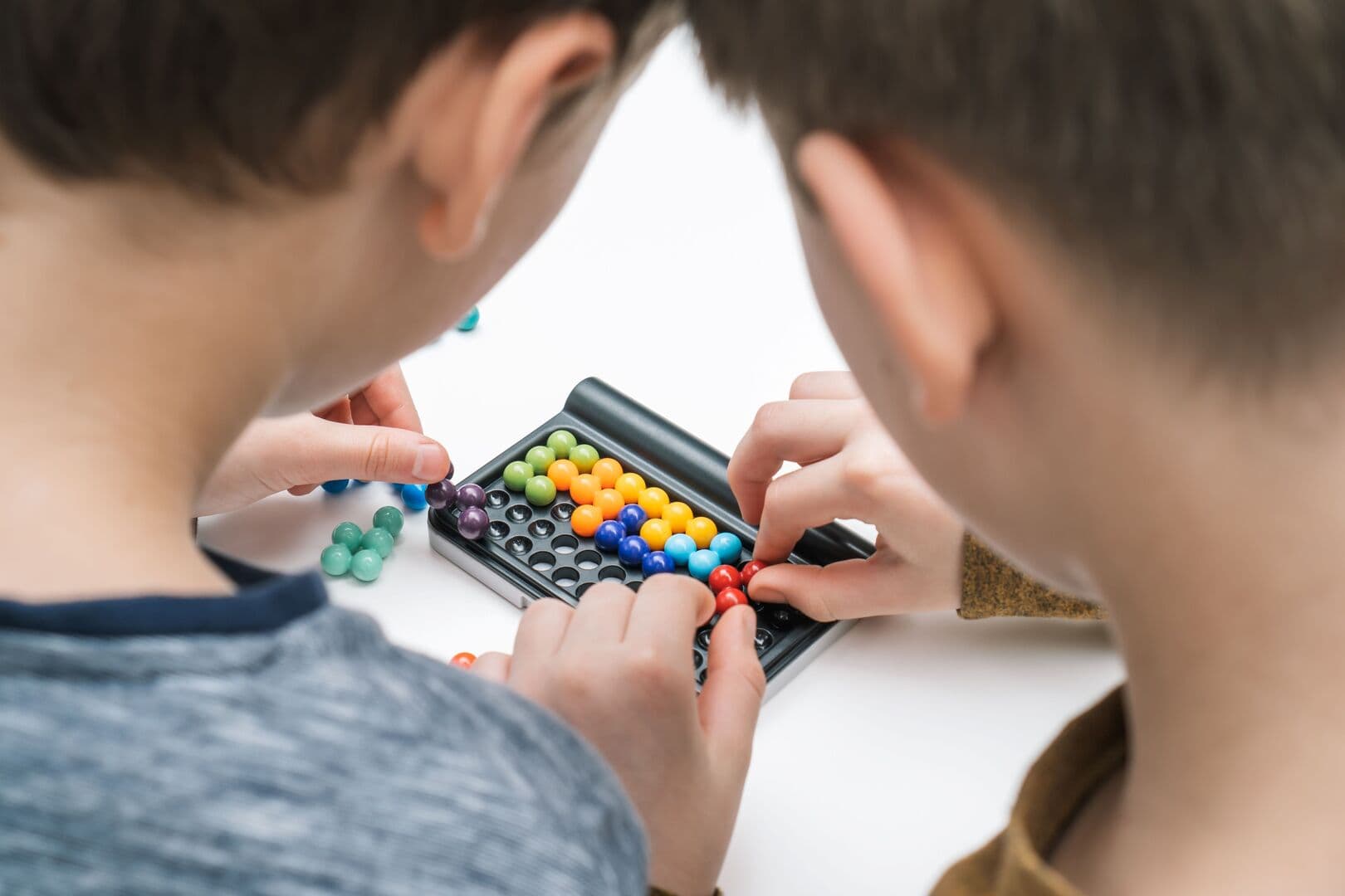 Twee kinderen leggen samen een kleurrijke kralenpuzzel