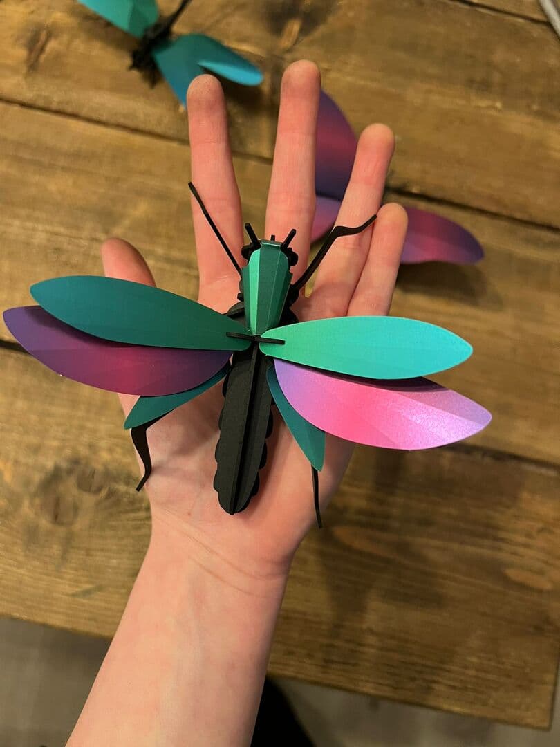 Hand met een kleurrijk papieren insect