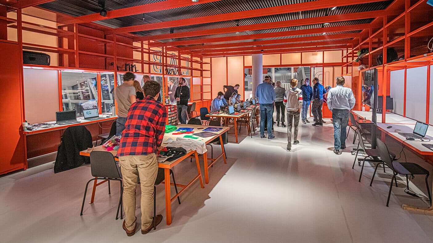 Bezoekers bij de werktafels en laptops in het oranje Smartlab van het Forum