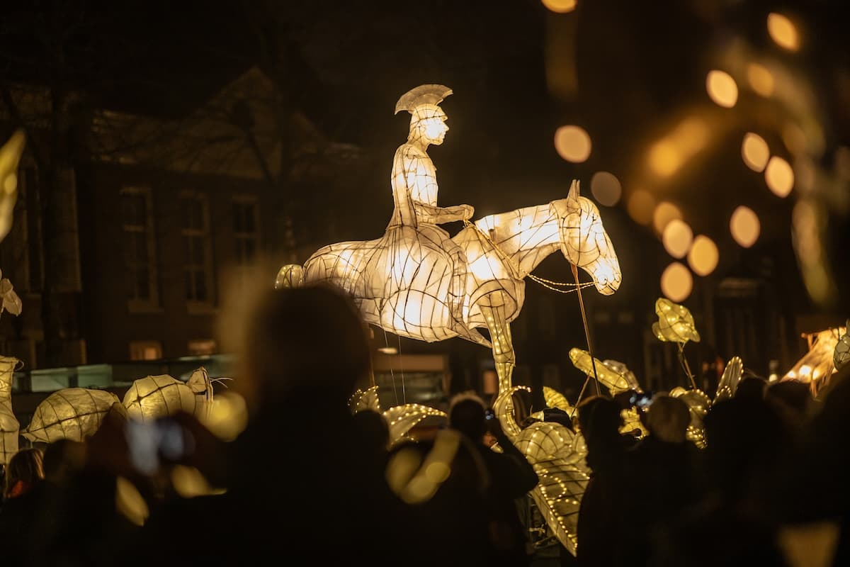 Verlichte sculptuur van Sint Maarten te paard boven het publiek tijdens de avondoptocht