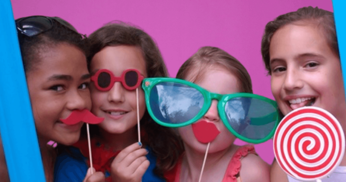 Kinderen poseren met grappige brillen en snorren in een photobooth